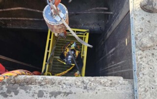 UCC diver being lowered into a intake tunnel for underwater inspection and maintenance.
