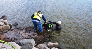 Two UCC commercial divers prepare to lower a remotely operated vehicle in the water to begin a long-distance tunnel inspection.